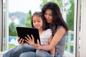 mother and girl holding e-book reader at home