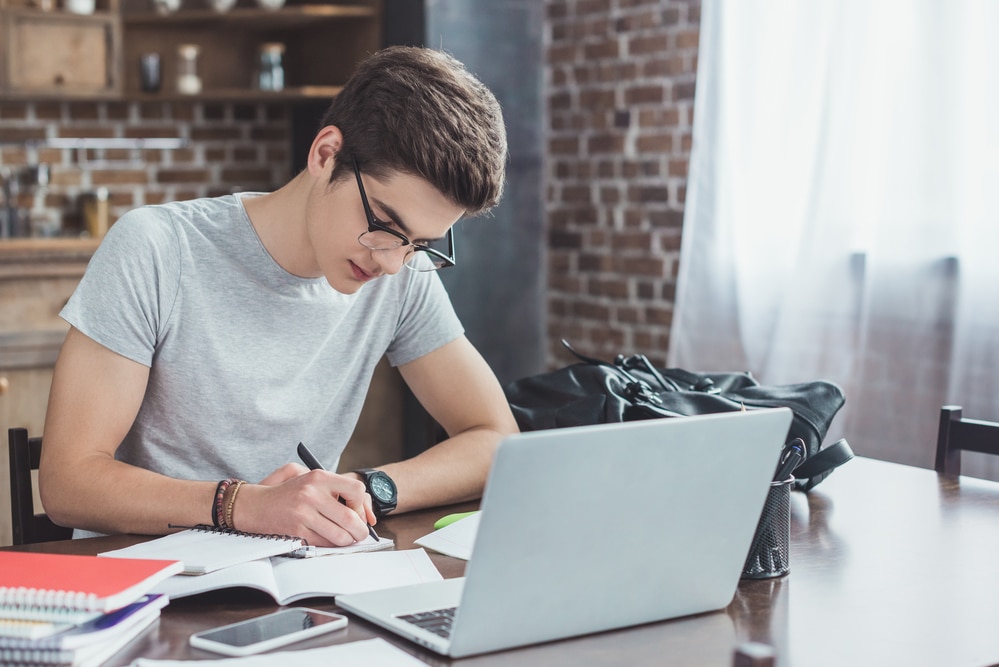 Student taking notes at a computer